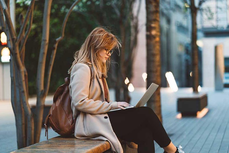 woman using a laptop on a city street